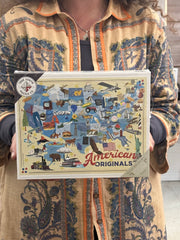 A person holding a 500-piece puzzle box featuring American-themed imagery.