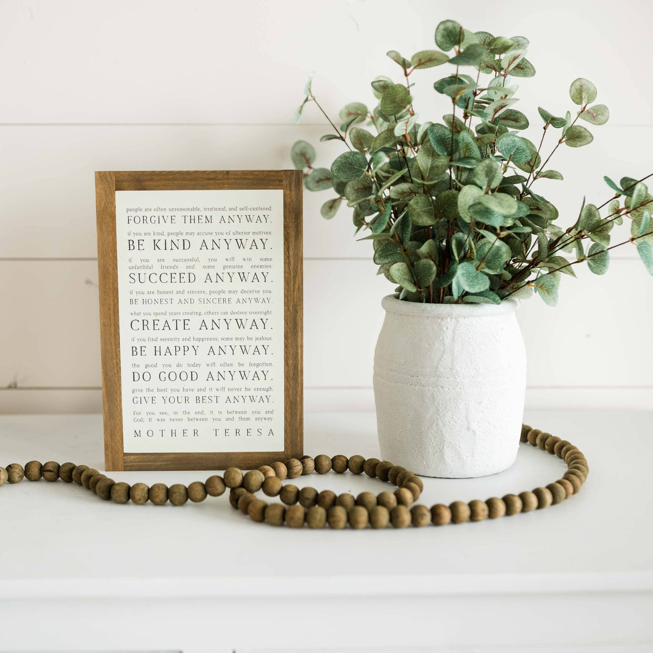 Love them Anyway | Mother Teresa | Wall Art: Soft White-Black Text / Dark Brown Frame / 8 inches x 12 inches Joyfully Said